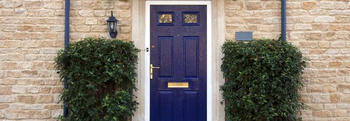 Fassade aus Stein, blaue Tür und Zwei Hecken